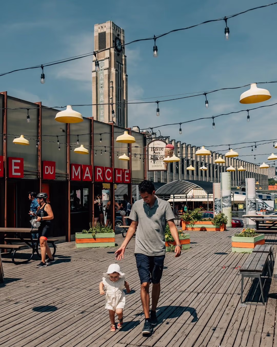 The Atwater Market boardwalk under string lights, its Art Deco clock tower rising behind the DU MARCHÉ sign