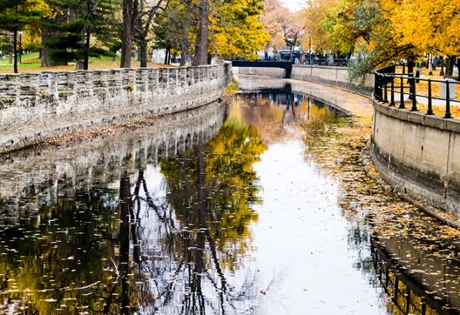 The Lachine Canal in autumn, stone lock walls and golden foliage mirrored in still water