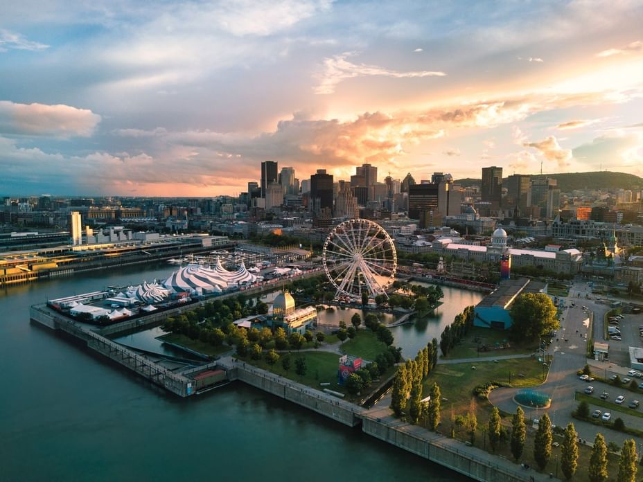 Aerial view of the Old Port at sunset — the Cirque du Soleil big top, the Grande Roue and the downtown skyline behind