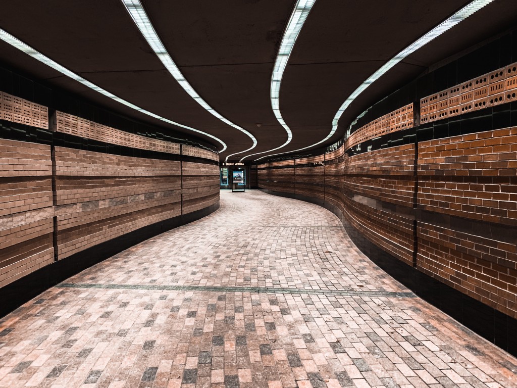 A curved, warm-brick-lined pedestrian tunnel of Montréal's Underground City near Square-Victoria