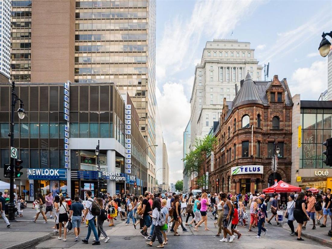 A summer crowd crossing rue Sainte-Catherine past the Sun Life building and the TELUS corner